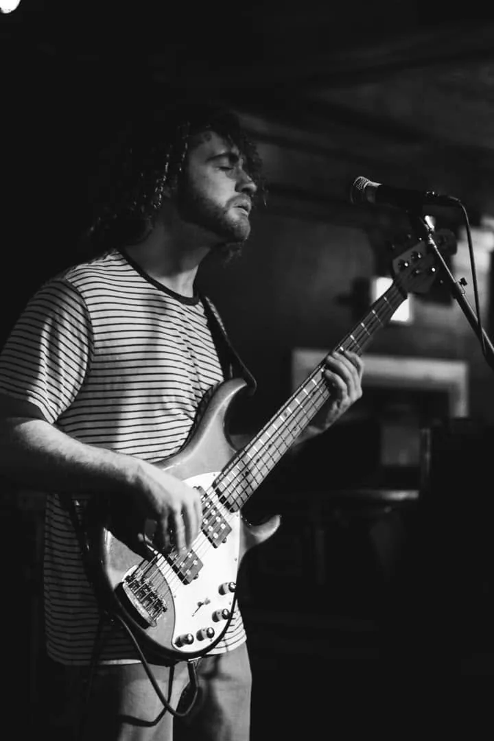 A bassist singing into the mic
